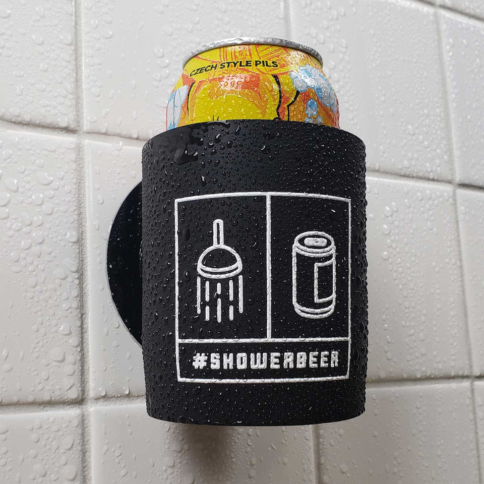 Foam can beverage holder that sticks to shower wall via industrial velcro. This design is white ink printed on a black can holder with the words "#SHOWERBEER" written across the bottom and the artwork depicting a shower head and a canned beer beverage. This is an action shot of the product in a shower.